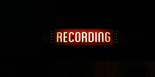 A red and white sign shows the word 'recording' against a black background