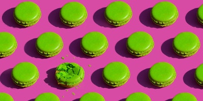 Green macarons on a pink background. One of them is smashed