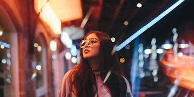 Woman walking along lit-up street at night