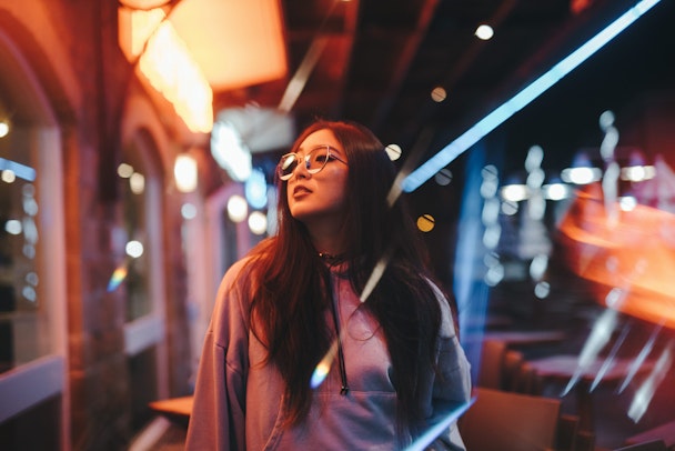 Woman walking along lit-up street at night