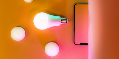 Lightbulbs and a mobile phone on an orange background