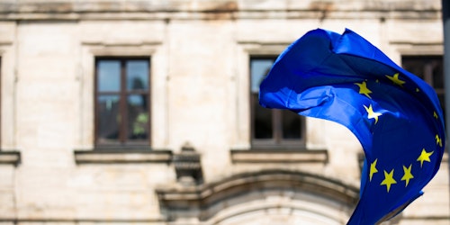 The European Union flag, waving in front of a building