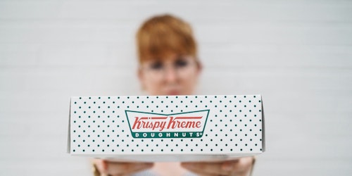 Person presenting a box of Krispy Kreme doughnuts