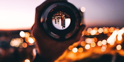 A city, reflected upside-down in a lens held by a hand