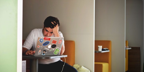 A man sitting at a desk pushing his fingers through his hair, looking stressed