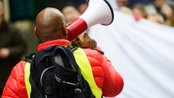 Black man with bald head holding megaphone 