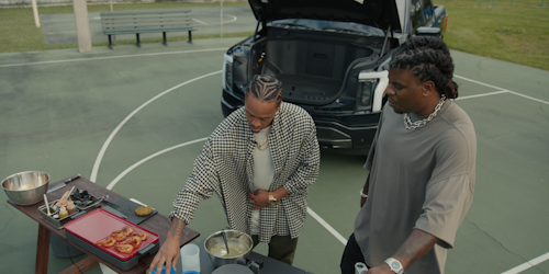 Ford F-150 Lightning front trunk open with two guys grilling in front of the truck