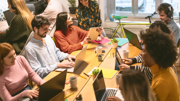 Work team sat around table on laptops