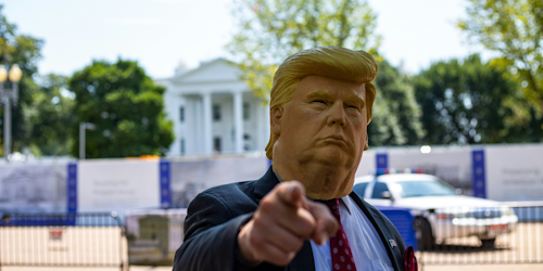 Man wearing Donald Trump rubber Halloween-style mask